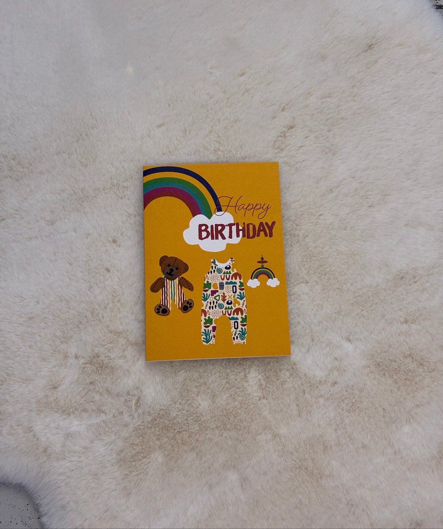 Small yellow birthday card with colorful design on a textured surface